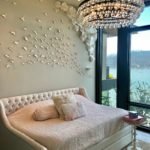 A bed with a chandelier and a large window in a house cleaning marin county