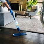 A home cleaner using a mop to clean a hardwood floor.