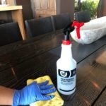 A person using a spray bottle and a yellow rag for house cleaning.