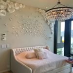 A beautifully adorned bedroom with a chandelier and flowers on the wall, impeccably maintained by professional home cleaners.
